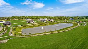 overhead view of a neighborhood with large homes around a manmade pond