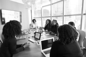 black and white photo of a group of women sitting at a table with computers