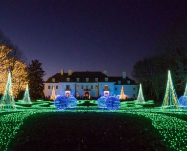 A lighted lawn in front of a large manor at Winterlights